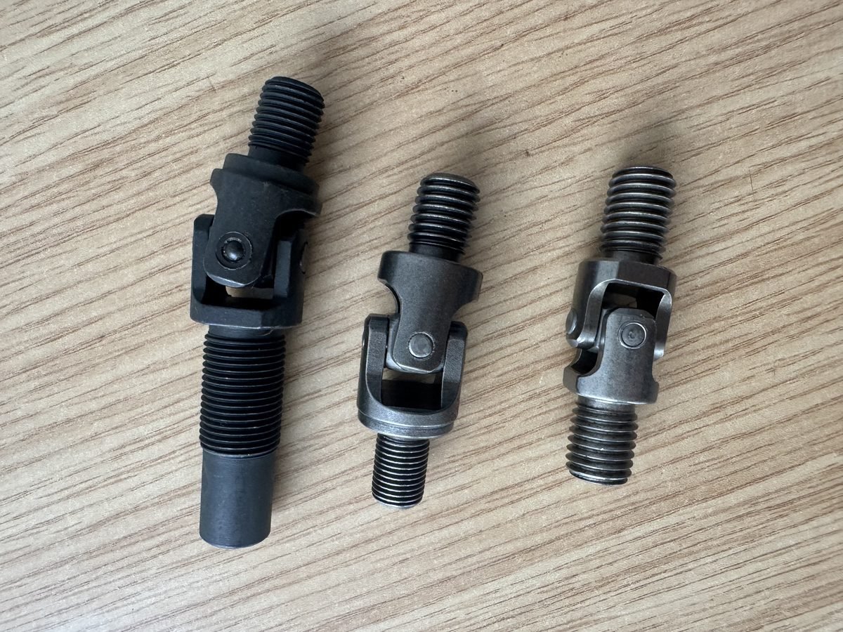 Three black universal joints with threaded ends for farm machinery, production photo